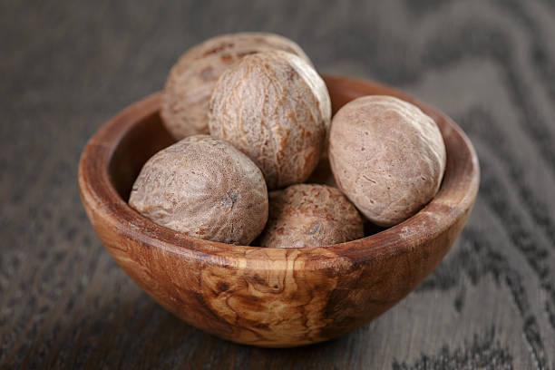 istock whole nutmegs in olive bowl on oak table, rustic 480818572