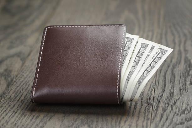 istock leather wallet on wood table with dollar bills 480819148