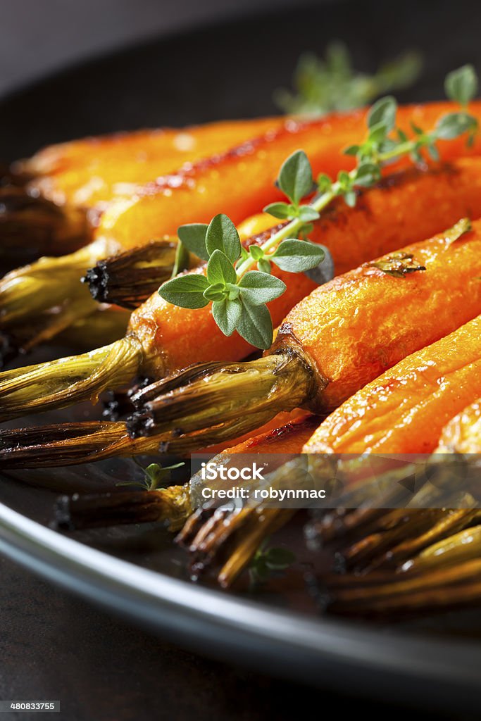 Roasted Baby Carrots with Thyme Roasted baby carrots with thyme, in black serving dish. Baby Carrot Stock Photo