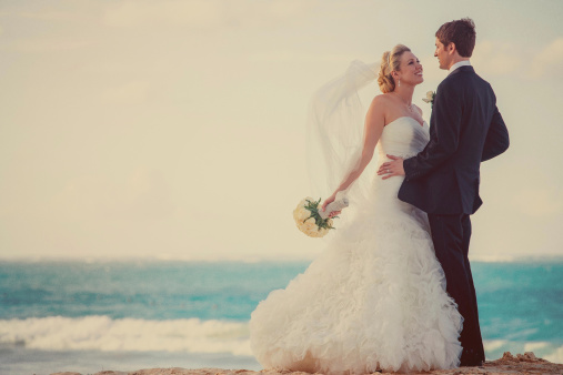 Bride and groom embracing at the beach