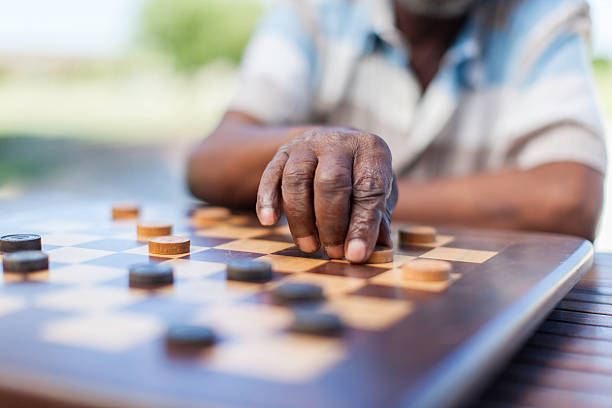 African senior playing chess, making a move African elder playing chess, making a move. Langebaan, Western Cape, South Africa. senior chess stock pictures, royalty-free photos & images