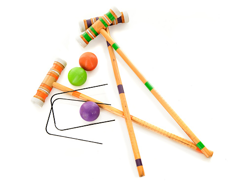 Overhead view of three wooden croquet mallets with matching balls and two black wickets.  On a white background.