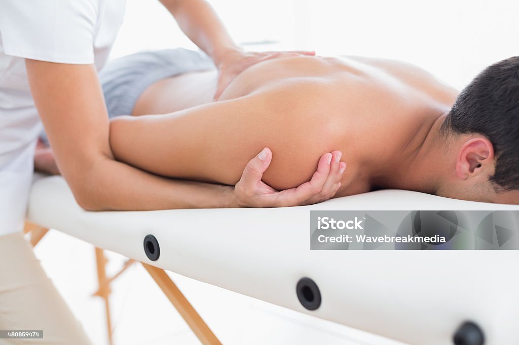 Physiotherapist doing shoulder massage to her patient Physiotherapist doing shoulder massage to her patient in medical office Massaging Stock Photo