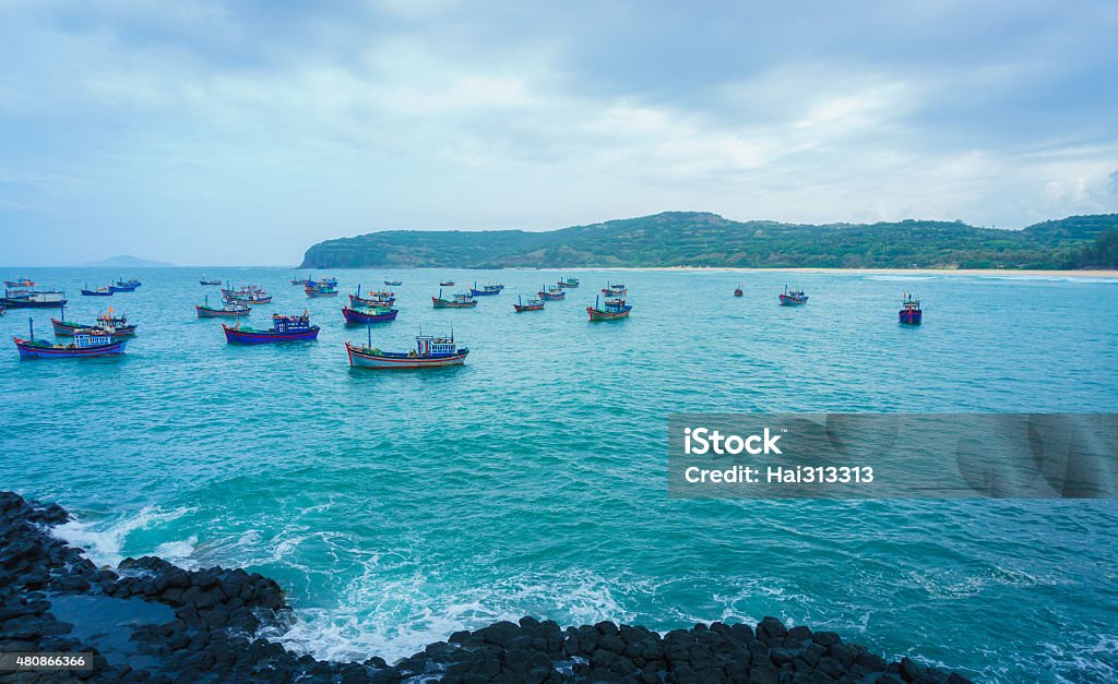 GanhDaDia giant's causeway and boats Tourists explore the Giant's Causeway, Ganh Da Dia, TuyHoa, PhuYen, VietNam. Huge basalt rocks rise out of the sea on coast 2015 Stock Photo