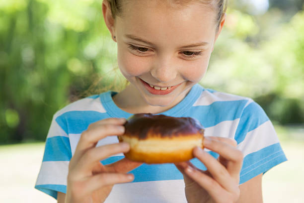 istock Cute little girl eating doughnut 480871828