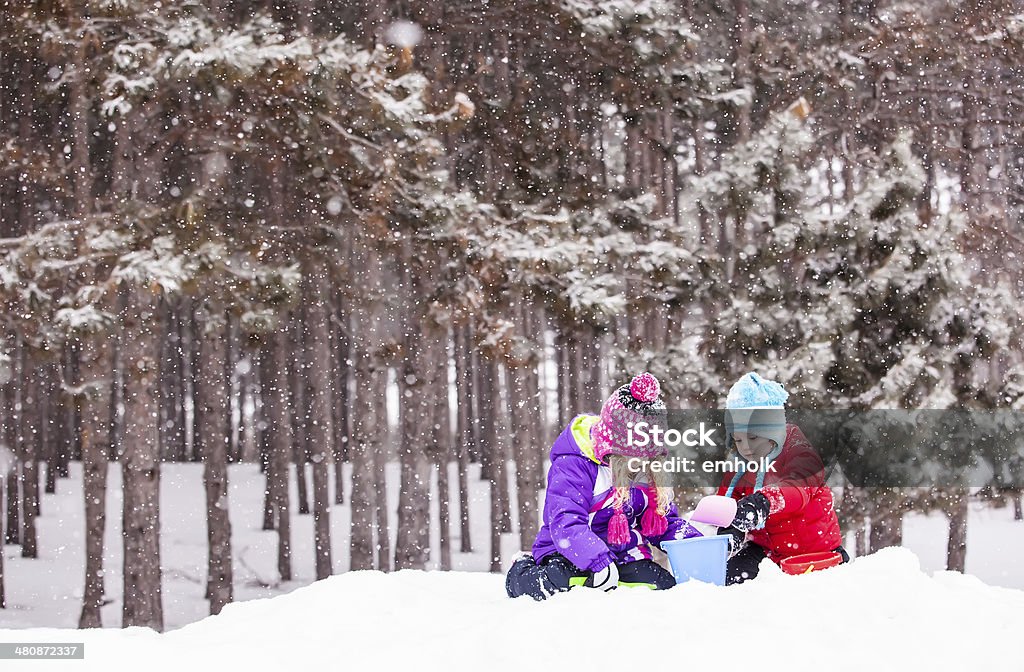 Girls Playing in Snow Two young girls (sisters) playing on a pile of snow while it is snowing. 4-5 Years Stock Photo