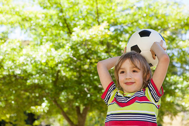 istock Happy little boy holding football 480873098