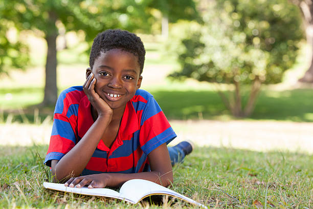 istock Little boy reading in the park 480877160