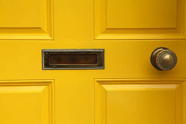 yellow door with letterbox and doorknob