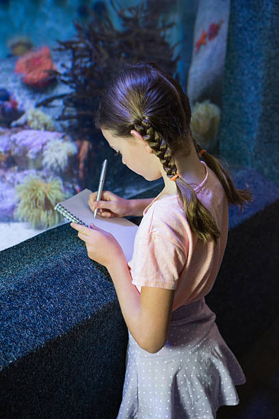 istock Cute girl looking at fish tank 480884372