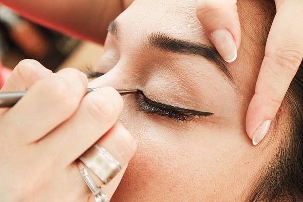 istock Makeup artist tracing eye line with black eyeliner 480888540