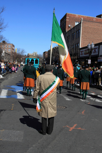 Stamford, USA - March 09, 2013: The individual is carrying the Irish flag in the annual St. Patrick's Day parade which is the second-largest after the Thanksgiving parade consisting of 80 marching units, 15 marching bands and many other entertainers.