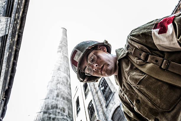 A USA Army WWII military soldier medic looks down helplessly at a combat casualty. First person POV image. Completely authentic World War II era United States Army military uniforms, weapons, equipment and activities performed by professional WW II reenactment actors and models.