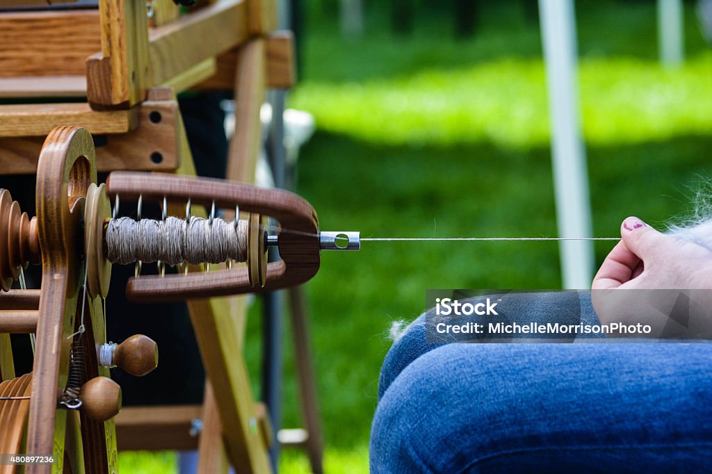 Close-Up Spinning Yarn on a Wheel Old fashioned spinning wheel for firber arts.  Spindle Stock Photo