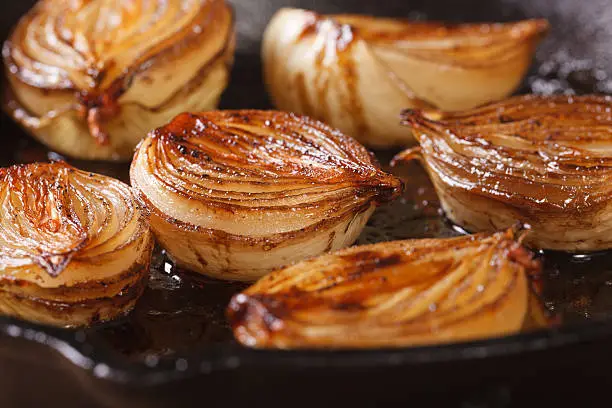 ñaramelized onion halves with balsamic vinegar in a pan close-up, horizontal