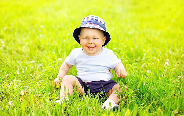 istock Cute smiling baby wearing a hat sitting on the grass 480917082