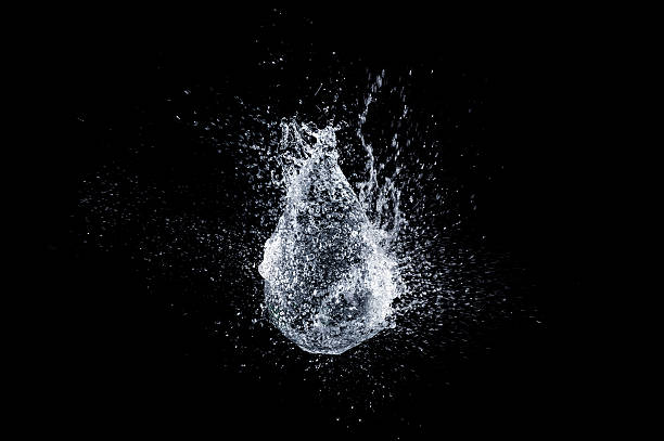 Water balloon Balloon bursting on black background. slow motion stock pictures, royalty-free photos & images