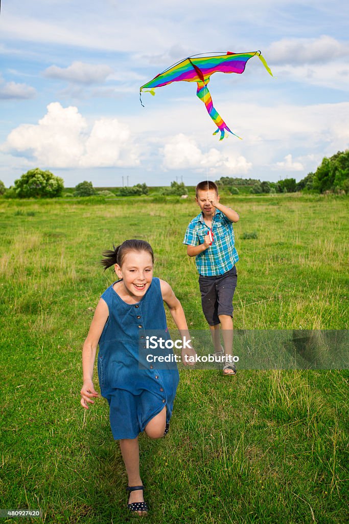 boy and girl flying  kite boy and girl flying  kite on a bright summers day. 2015 Stock Photo