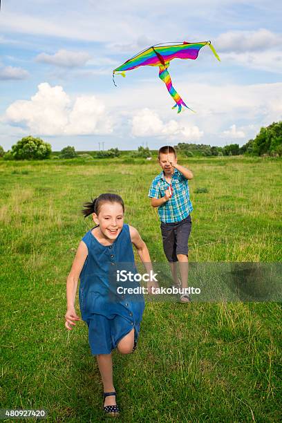 Boy And Girl Flying Kite Stock Photo - Download Image Now - 2015, Adult, Blue