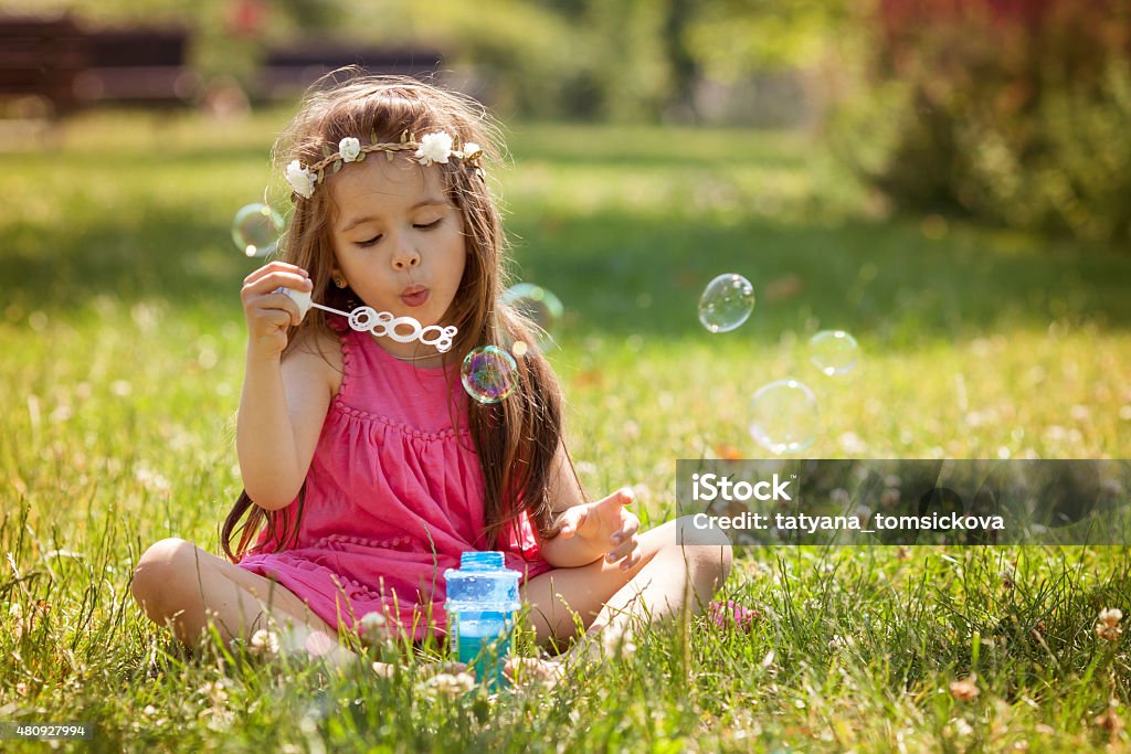 Beautiful portrait of sweet lovely little girl blowing soap bubb Beautiful portrait of sweet lovely little girl blowing soap bubbles in the park, summertime 2015 Stock Photo