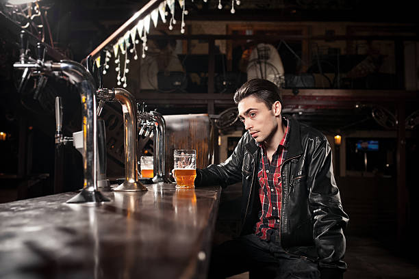 istock was a hard day. Depressed  man drinking beer in bar 480935820