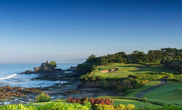 Morning view of a golf course and Tanah Lot temple in Bali.
