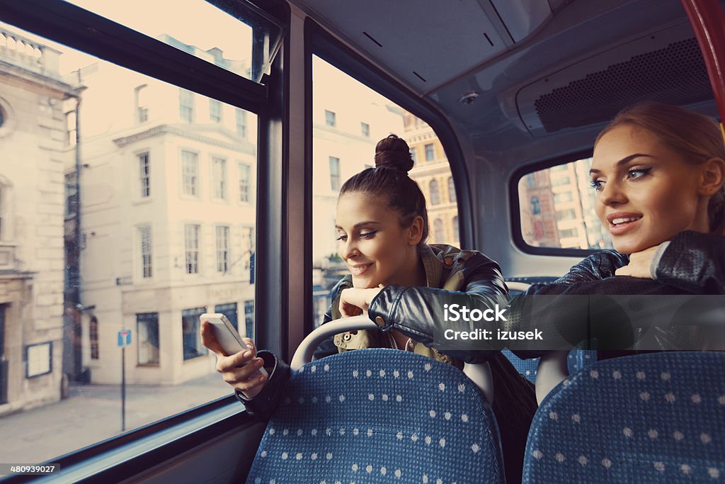 Friends on the public bus Two young women sitting on the bus, one of them using smart phone. Bus Stock Photo