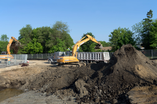 Kitchener, Canada - May 24, 2012: A large construction excavator removes contaminated soil from an urban brownfield development site. Brownfield properties are vacant or underutilized places where past industrial or commercial activities may have left contamination (chemical pollution) behind, including: factories, gas stations, waterfront properties (port lands) formerly used for industrial or commercial activities.