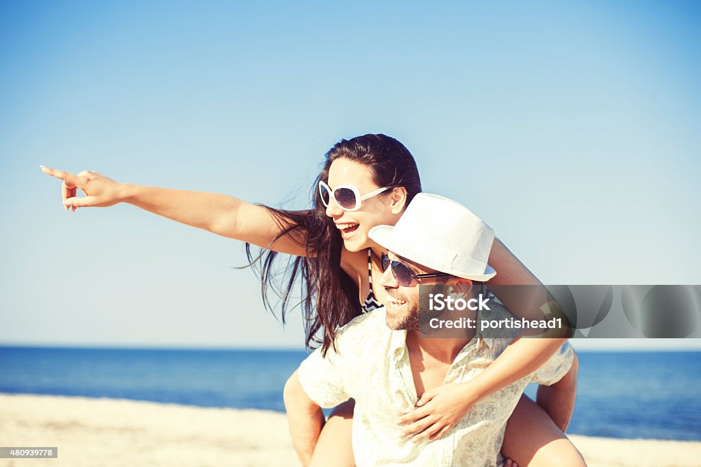 Happy young couple having fun Happy beautiful young couple enjoying their vacation on the beach. Both of them are caucasian ethnicity and wearing white sunglasses. Concept for love, freedom and hapiness 2015 Stock Photo