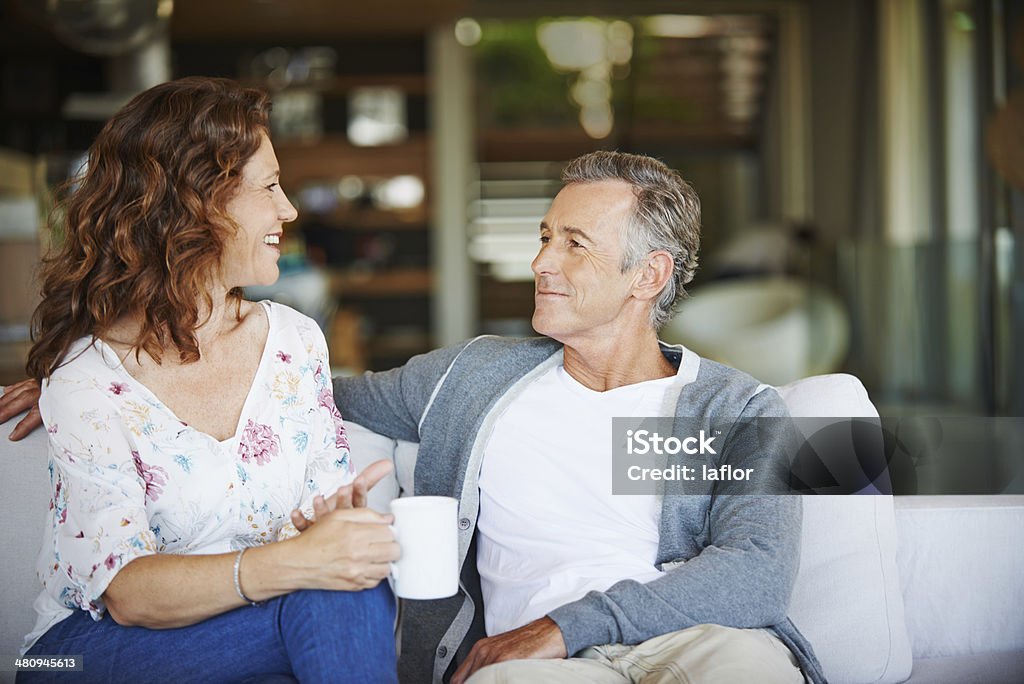 We should do this more often! A happy mature couple enjoying a cup of coffee together on the sofa at home Adult Stock Photo