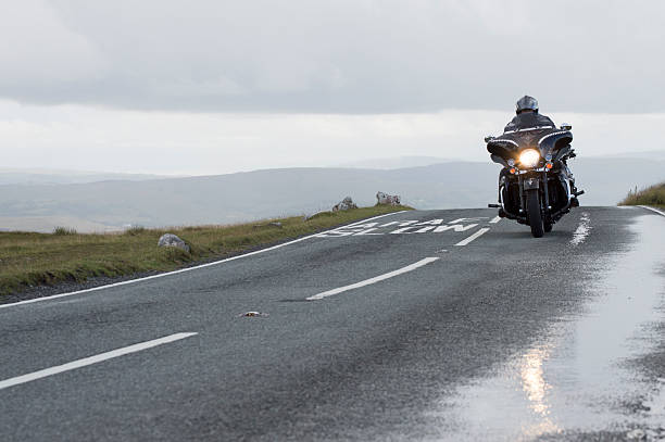 uomo su una moto su strada di montagna in bianco montagne - harley davidson foto e immagini stock