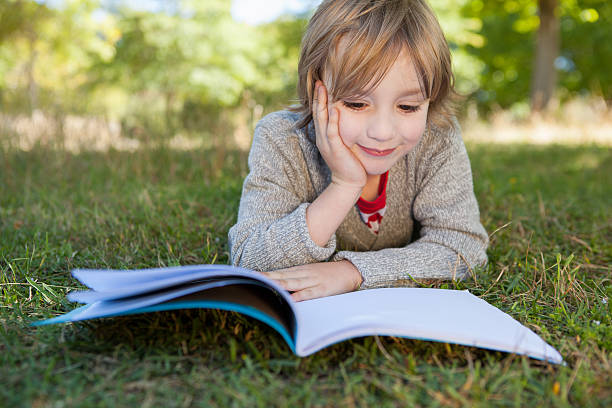 istock Cute little boy reading in park 480947772