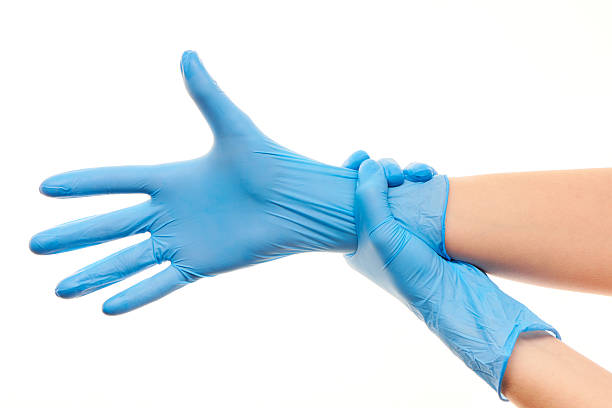 femmina dottore mani mettendo su blu guanto chirurgico sterilized - rubber sports glove equipment isolated foto e immagini stock