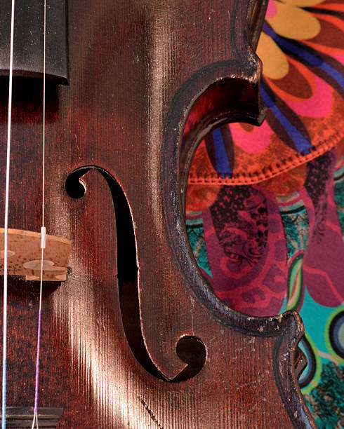 Antique violin closeup against bright print Closeup of a violin against a bright, artsy fabric background. Violin is an antique from the early 1800's in a dark stain (original finish). violin f hole stock pictures, royalty-free photos & images