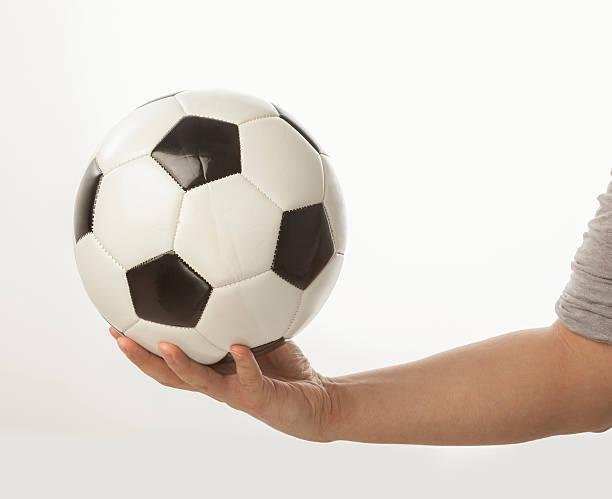 Hand holding football ball on white background stock photo