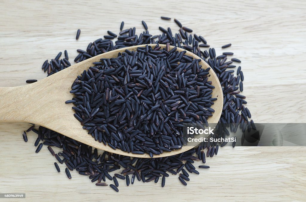 Rice berry in a wooden ladle, on wood table. Agriculture Stock Photo