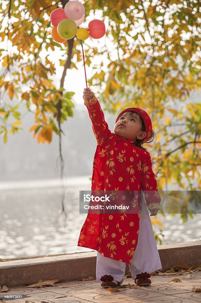 Baby girl Baby girl in traditional dress plays with balloons Ao Dai Stock Photo