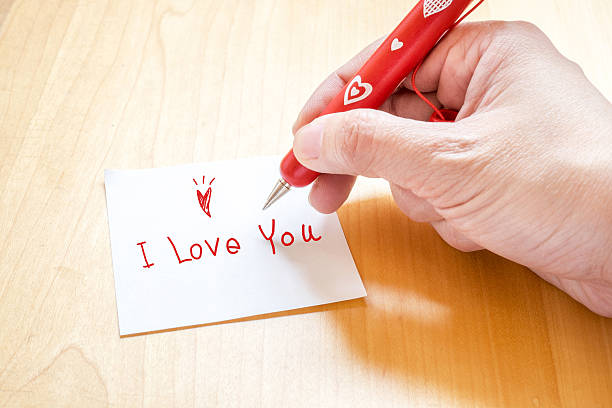 istock Hand holding pen writing I love you 480980398