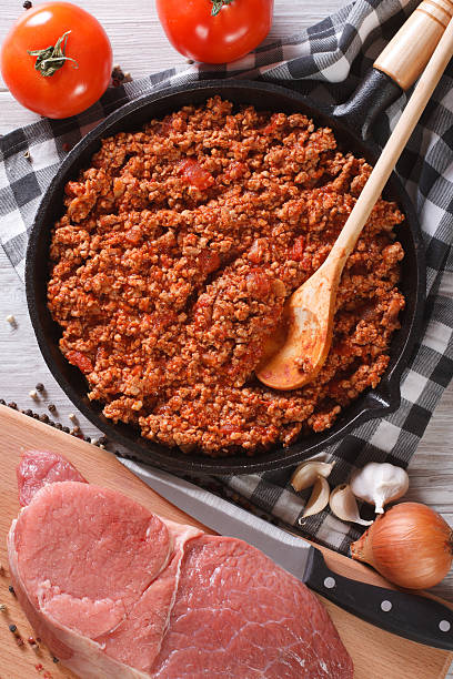 istock Bolognese sauce in pan and ingredients vertical top view closeup 480981032