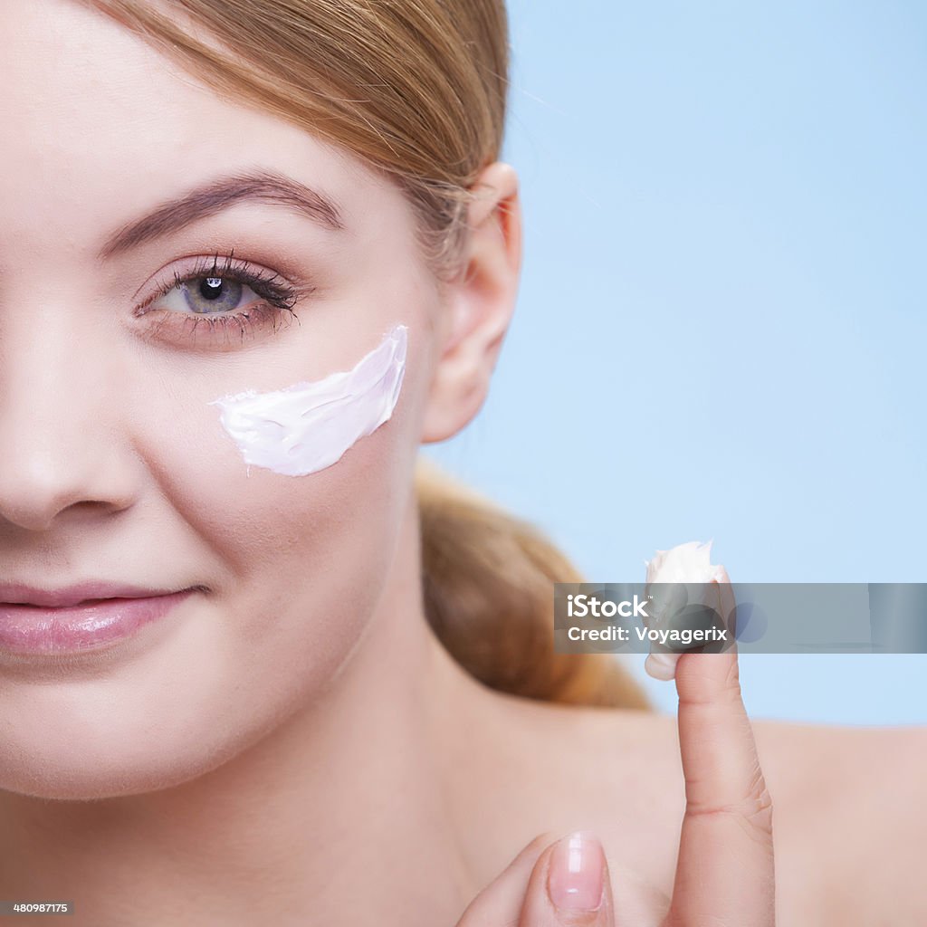 Skincare. Face young woman girl taking care of dry skin. Skincare habits. Part of face of young woman as symbol of red capillary skin on blue. Girl taking care of her dry complexion applying moisturizing cream. Beauty treatment. Adult Stock Photo