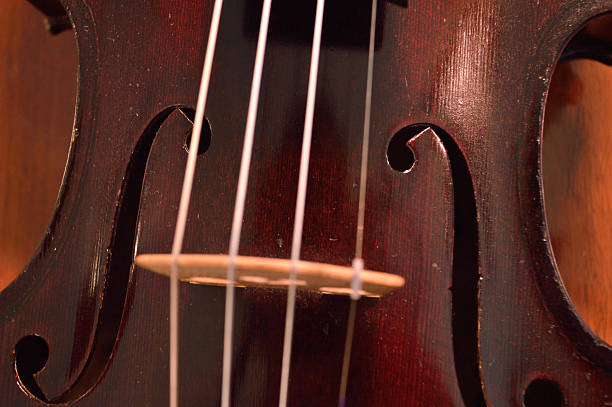 Antique violin closeup against wood Closeup of old violin against wood background. Violin is an antique from the early 1800's in a dark stain (original finish). violin f hole stock pictures, royalty-free photos & images
