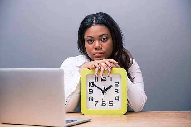 istock Tired businesswoman sitting at the table with clock 480990856