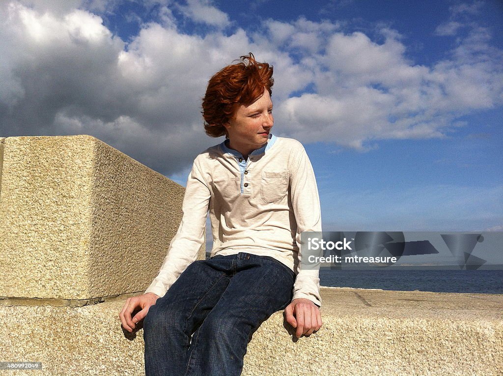 Red headed boy sat on seawall in sunshine Close-up photo of Red headed boy sat on seawall on a sunny day. Aspirations Stock Photo