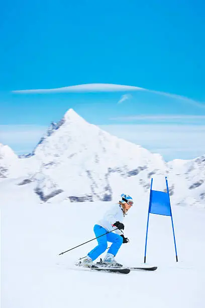 Giant slalom race. Girl skier, snow skiing carving at high speed. A beautiful snowy mountain landscape in the background. Switzerland Zermatt region, mountain Matterhorn