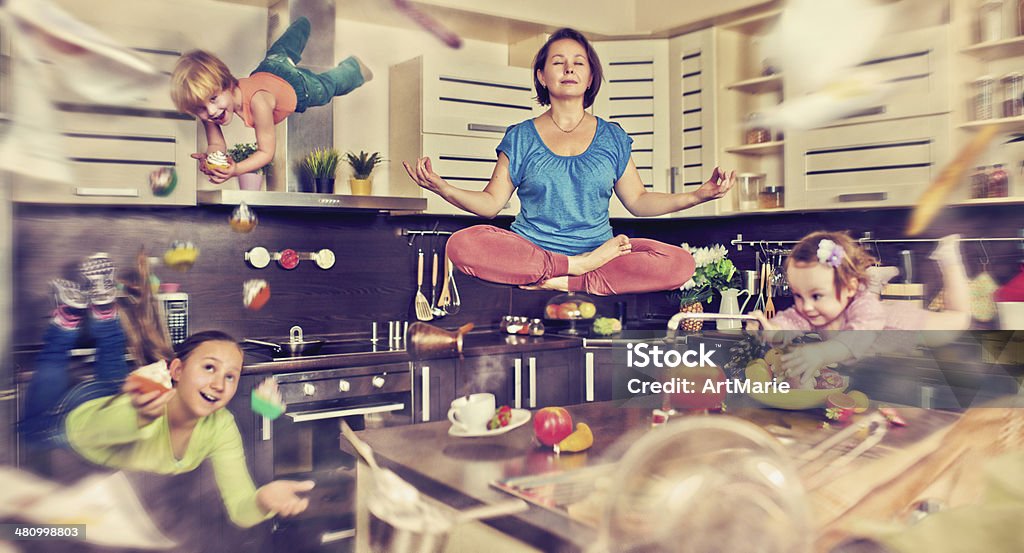 It's time to fly away Mother meditating at the kitchen with her children flying around Chaos Stock Photo