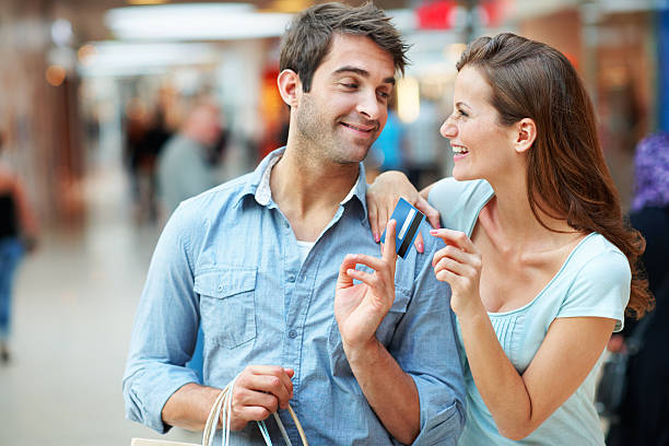 Anything for you! An attractive couple holding their credit card and purchases in their local mall clothing store credit card stock pictures, royalty-free photos & images