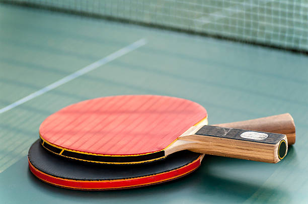 zwei tennis schläger auf dem tisch mit einem gitter - table tennis tennis table indoors stock-fotos und bilder