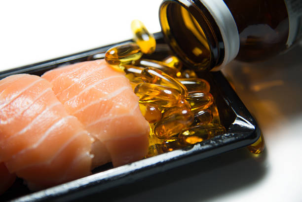 魚オイルを注ぎ、薬でお出しする寿司サーモンの絶縁 - fish oil healthy eating capsule isolated ストックフォトと画像