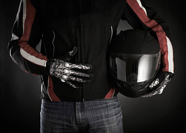 Motorcyclist with helmet in his hands. Dark background stock photo