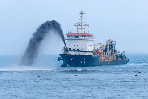 Spout of a dredger at work to reclaim beach erosion.